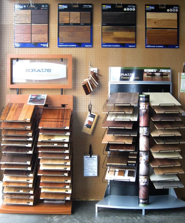 The laminate and hardwood sample wall in the Bellingham showroom, with plank samples on racks.