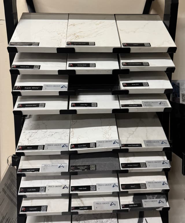 Quartz countertop samples on a display rack at the warehouse, in whites and greys with veined patterns.