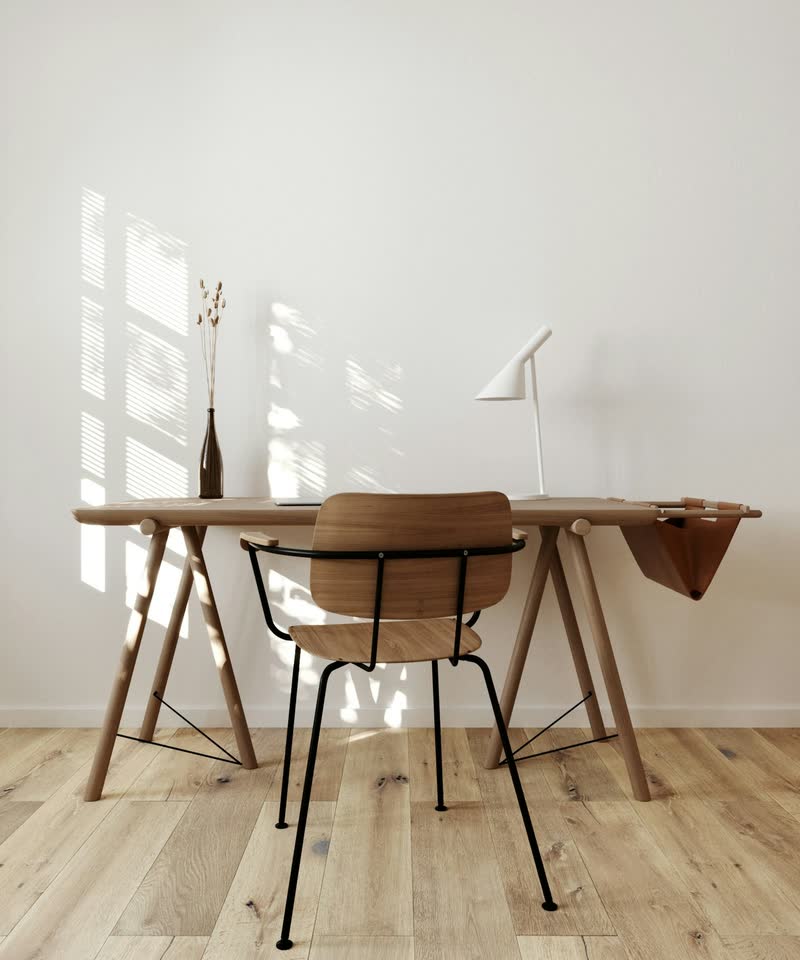 A wooden desk and chair on a light wood-look plank floor in a bright room.