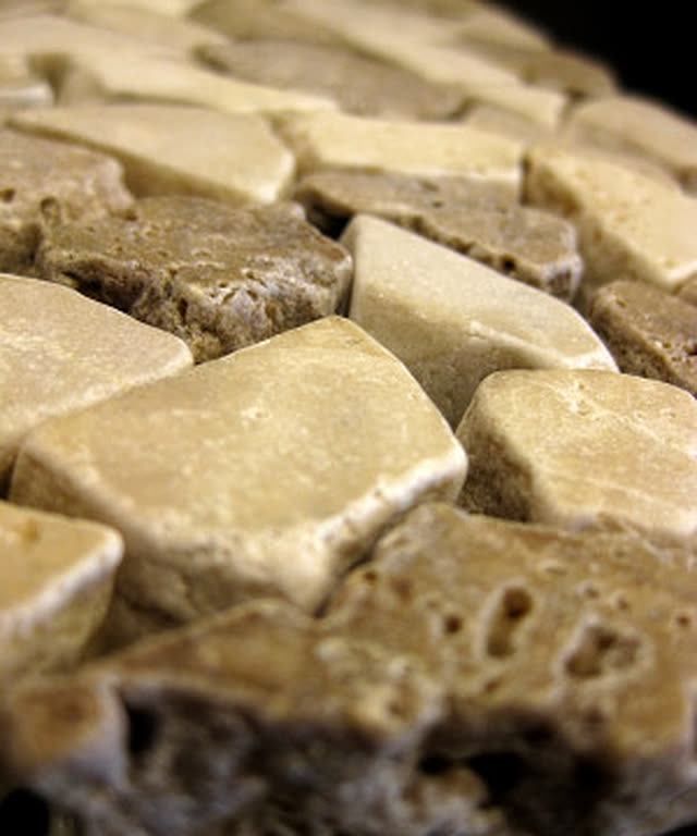 Tumbled travertine stone tile in warm honey tones, close up.