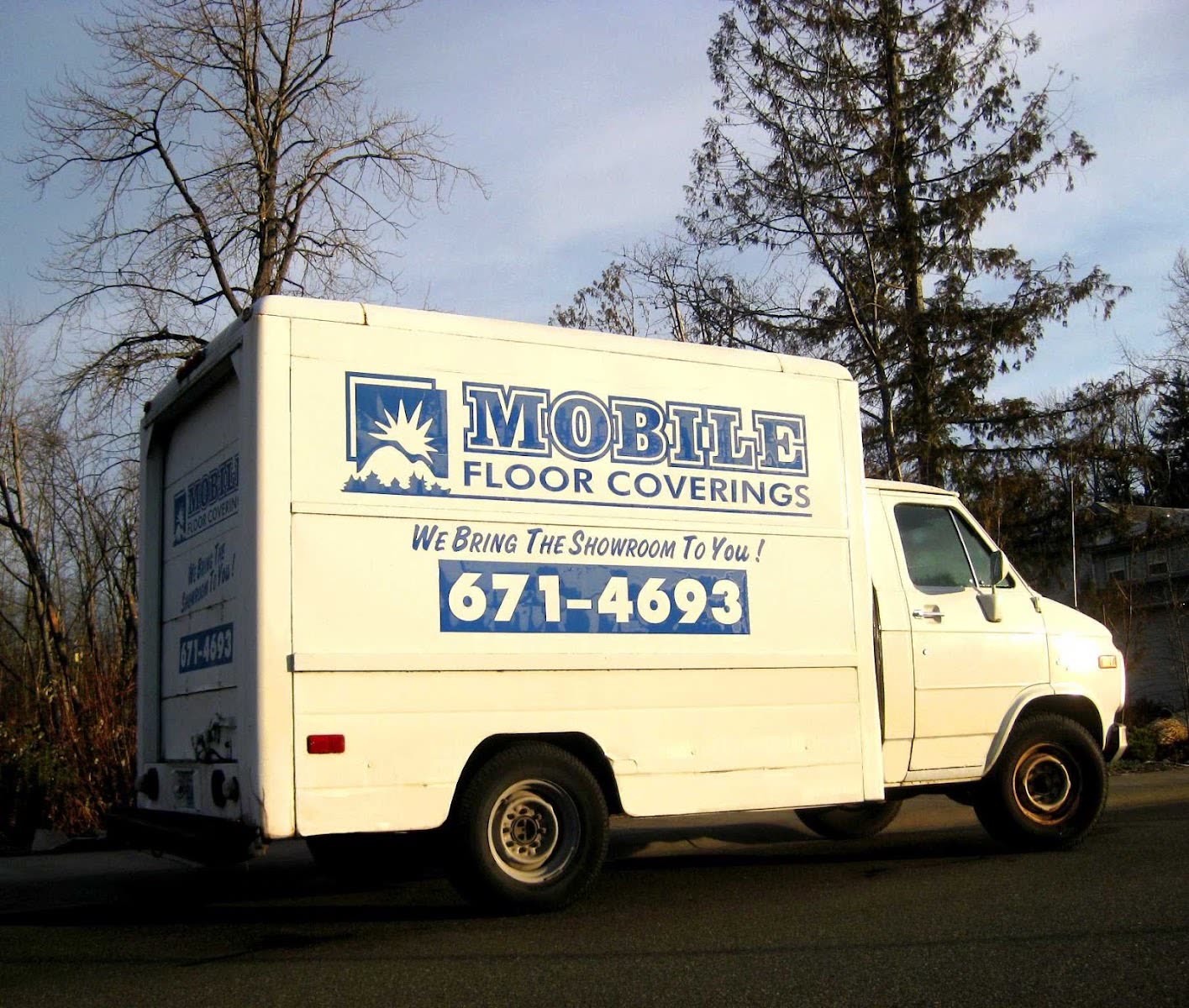 The Mobile Floor Coverings box van parked in Bellingham at sunset, with the
              company logo, the line We Bring The Showroom To You and the phone number
              671-4693 painted on the side.
